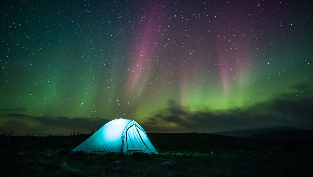 Glowing Dome Tent Beneath Northern Lights Over Remote Tussock Plain at Night