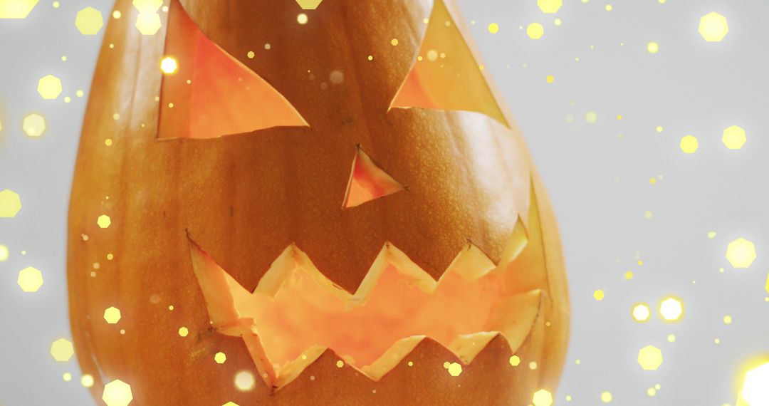 Close-up Carved Jack-o'-Lantern Emitting Warm Glow with Golden Bokeh Lights