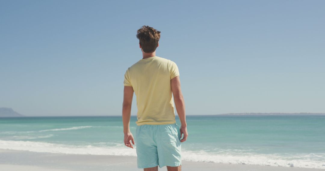 Man in Yellow T-Shirt and Blue Shorts Standing on Beach - Free Images, Stock Photos and Pictures on Pikwizard.com