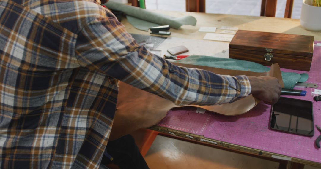 Craftsman Unrolling Leather in Workshop