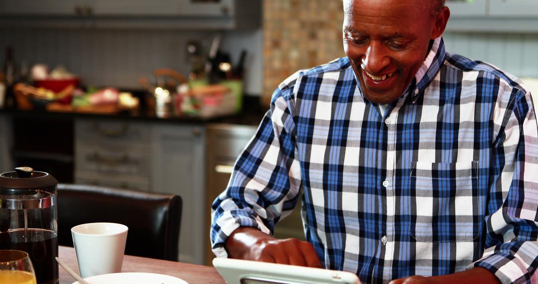 Senior Man Using Tablet in Kitchen Brightly Smiling - Free Images, Stock Photos and Pictures on Pikwizard.com