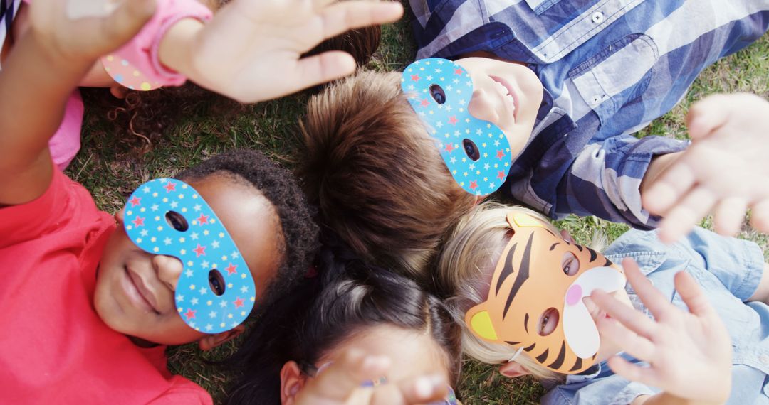 Children Lying on Grass Wearing Colorful Masks and Smiling - Free Images, Stock Photos and Pictures on Pikwizard.com