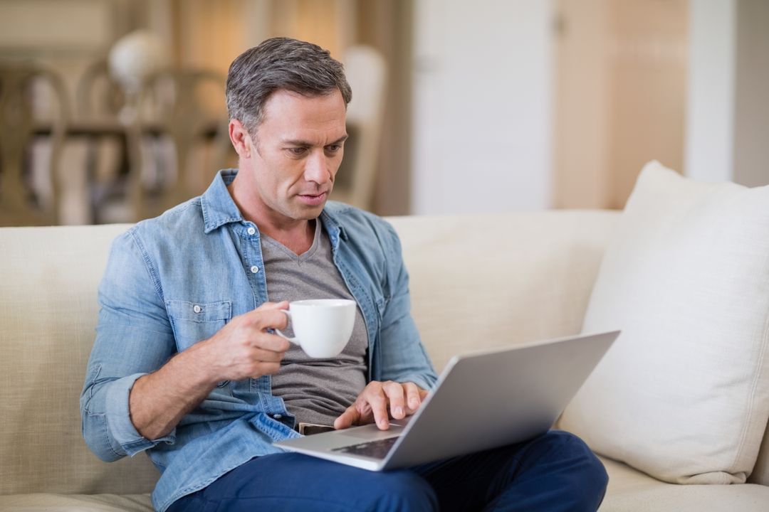 Man Working on Laptop While Drinking Coffee at Home - Free Images, Stock Photos and Pictures on Pikwizard.com