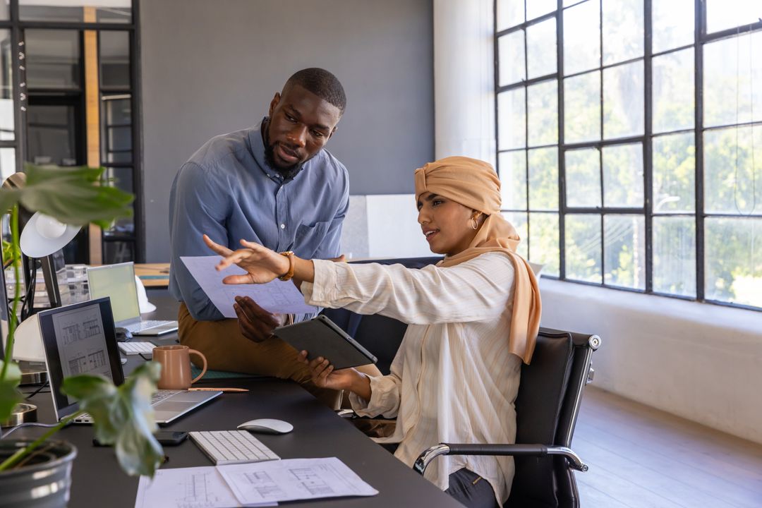 Diverse Coworkers Analyzing Blueprints in Modern Office Setting