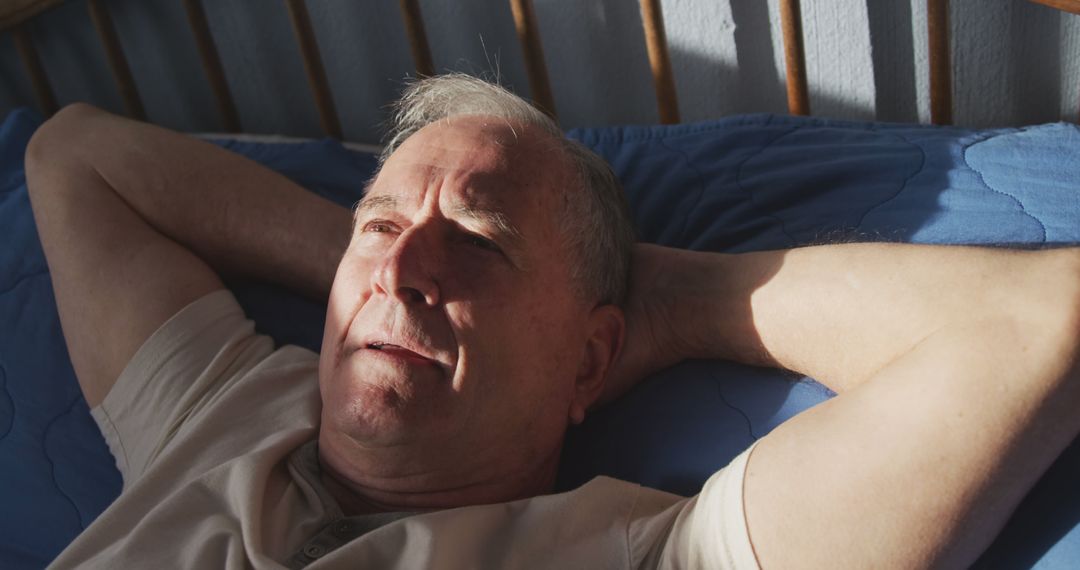 Senior man relaxing in bed with thoughtful expression - Free Images, Stock Photos and Pictures on Pikwizard.com