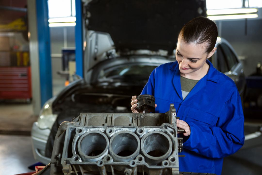 Female Mechanic Inspecting Engine Piston in Workshop