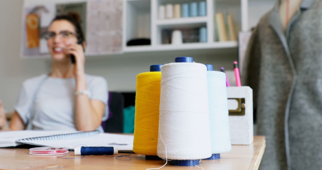 Female Fashion Designer Working in Studio with Thread Spools on Desk - Free Images, Stock Photos and Pictures on Pikwizard.com