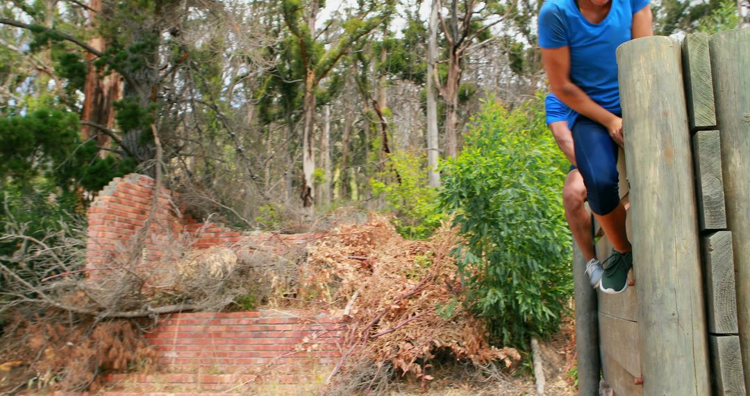 Energetic exercise climbing over fence in wooded terrain