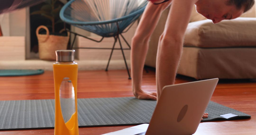 Focused Woman Doing Yoga at Home with Laptop and Water Bottle - Free Images, Stock Photos and Pictures on Pikwizard.com