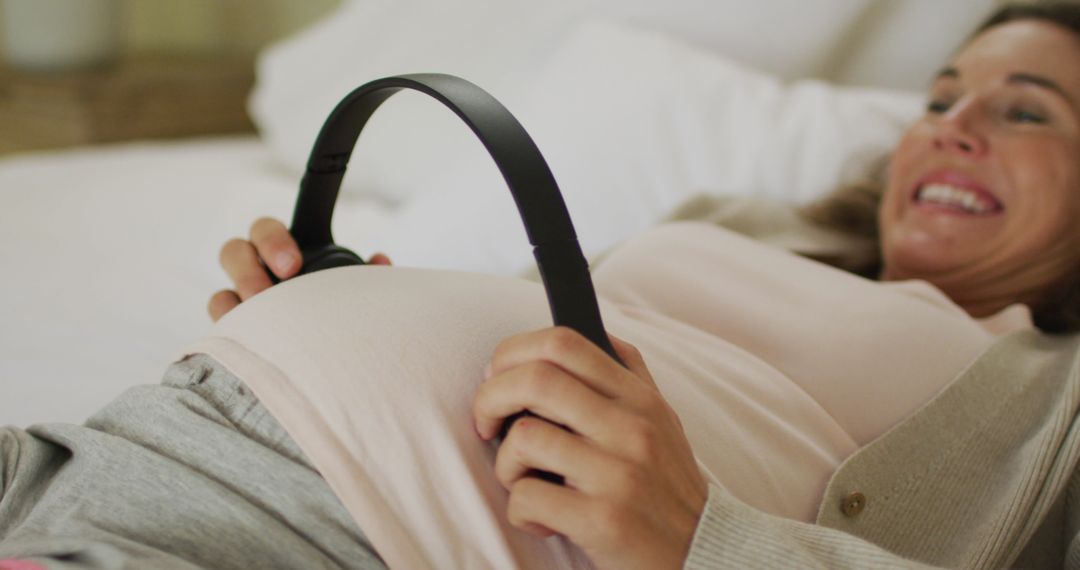 Pregnant Woman Holding Headphones to Belly for Unborn Child's Musical Joy