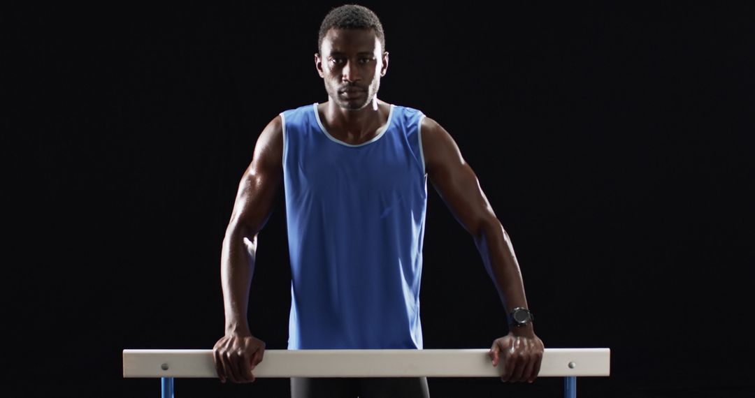 Athlete in Blue Tank Top Gripping Parallel Bars with Intensity