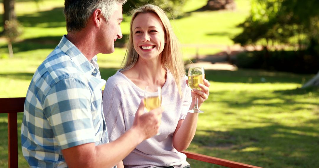 Middle-Aged Couple Toasting Wine in Park Setting with Smiles