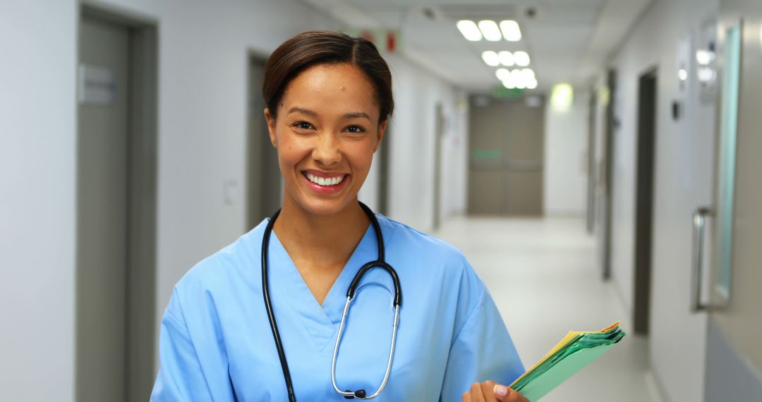 Smiling Nurse in Hospital Corridor Holding Patient Files - Free Images, Stock Photos and Pictures on Pikwizard.com