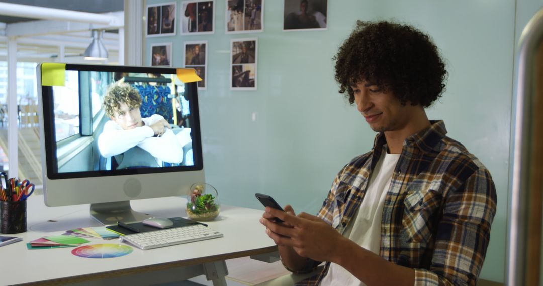 Smiling Man Using Smartphone at Workspace with Desktop - Free Images, Stock Photos and Pictures on Pikwizard.com