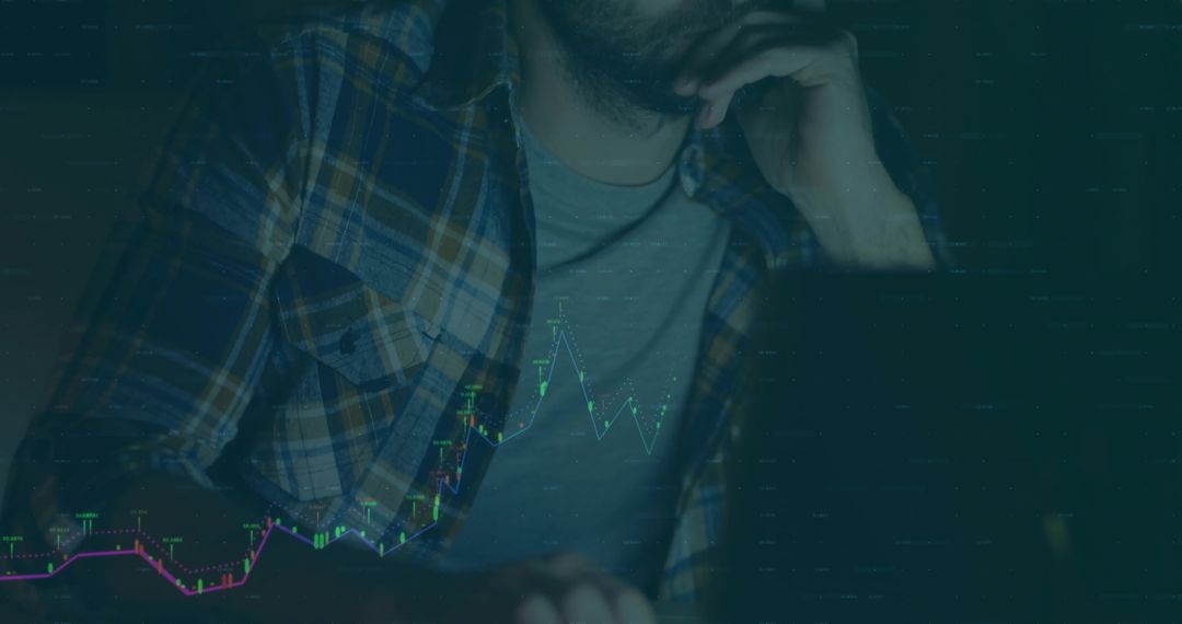 Man Analyzing Financial Trends on Laptop with Glowing Charts at Night