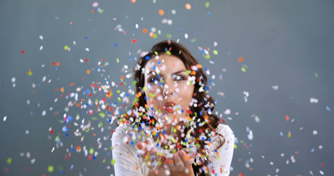 A young Caucasian woman blows colorful confetti from her hands, with copy space - Free Images, Stock Photos and Pictures on Pikwizard.com
