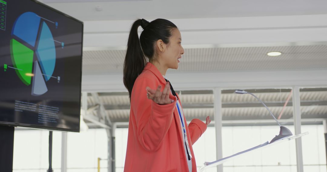 Asian Businesswoman Presenting at Conference with Data Screen