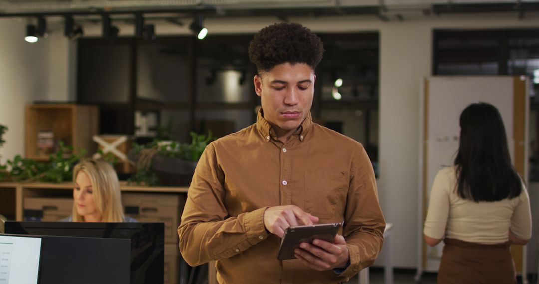 Image of focused biracial man with tablet working late in office - Free Images, Stock Photos and Pictures on Pikwizard.com