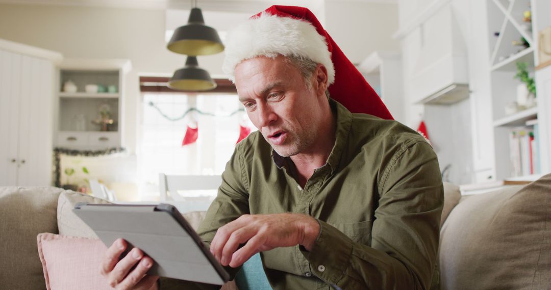 Middle-aged Man with Santa Hat Video Calling on Tablet during Christmas - Free Images, Stock Photos and Pictures on Pikwizard.com