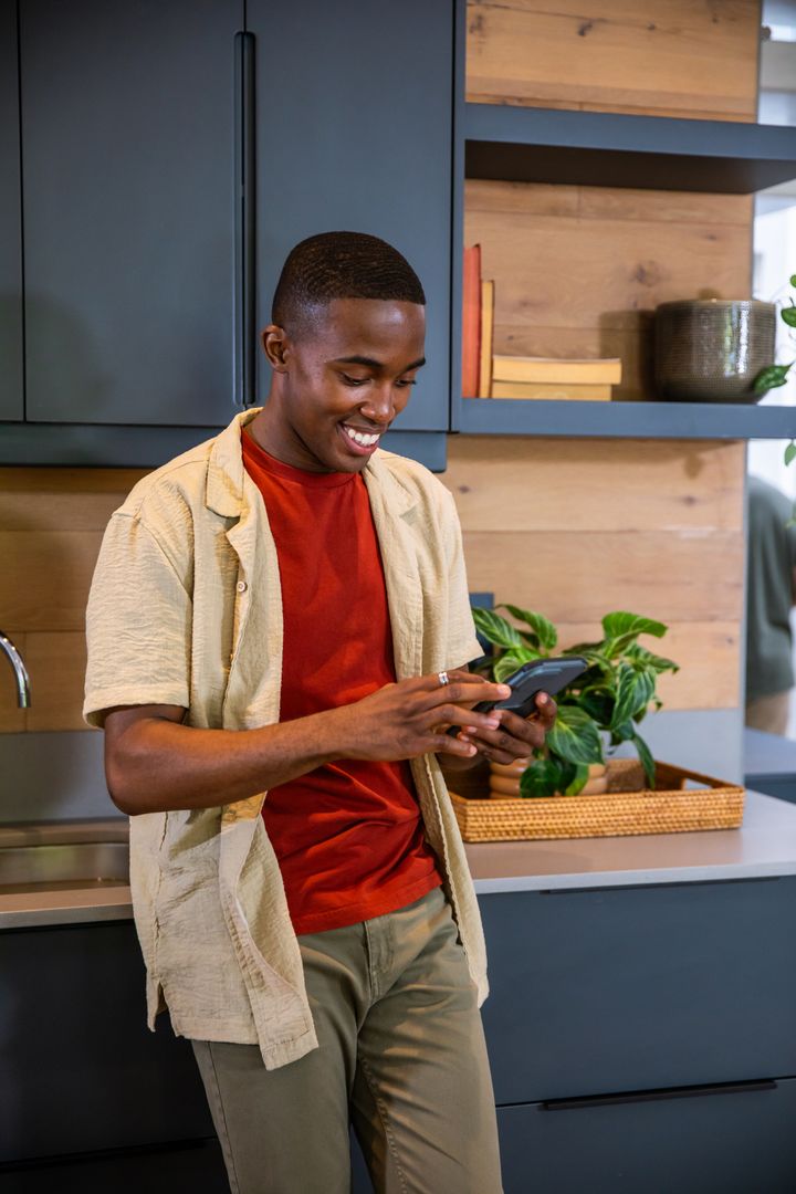 Young Man Engaging with Smartphone on Stylish Kitchen Counter
