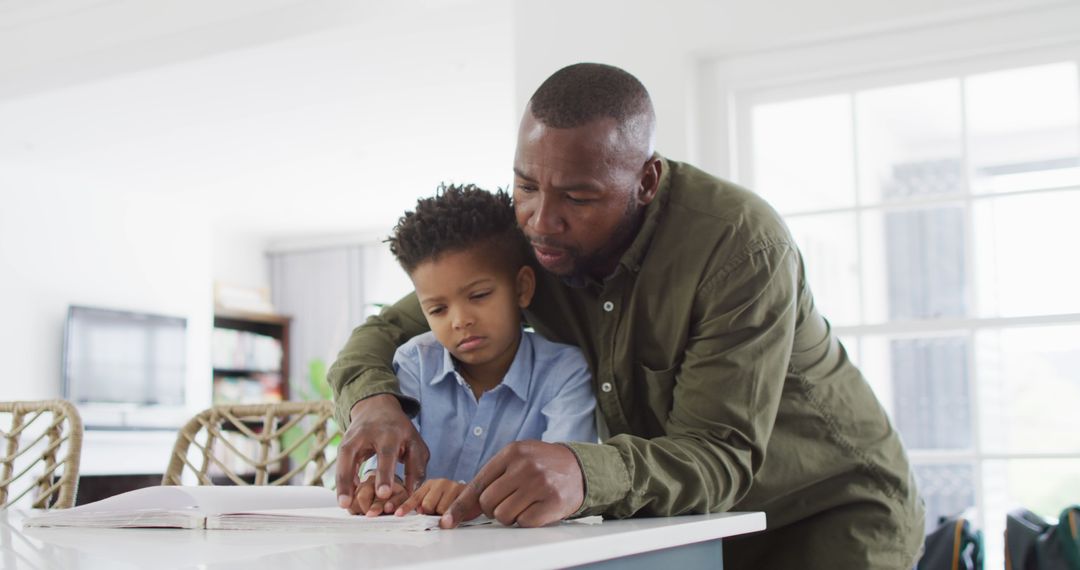 Father Helping Young Boy with Homework in Kitchen - Free Images, Stock Photos and Pictures on Pikwizard.com