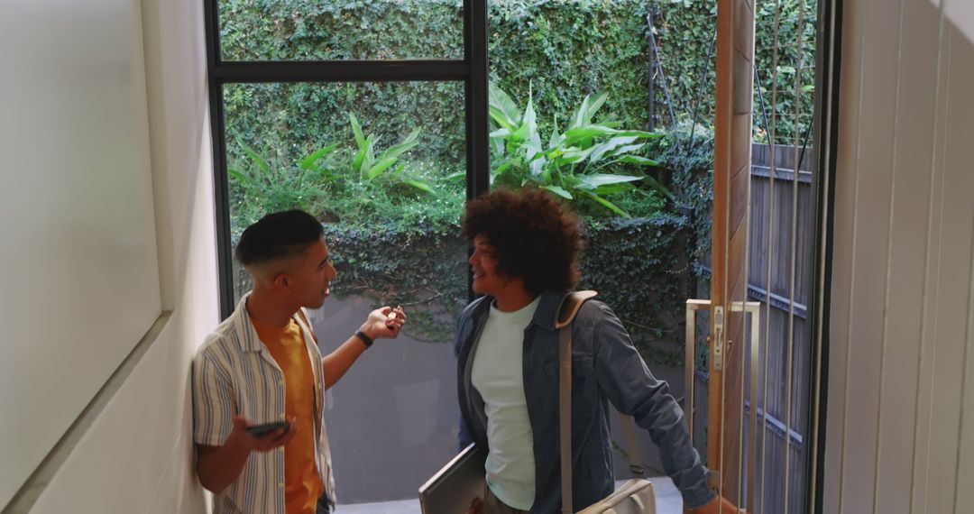 Diverse friends gesturing at entryway with laptop cases