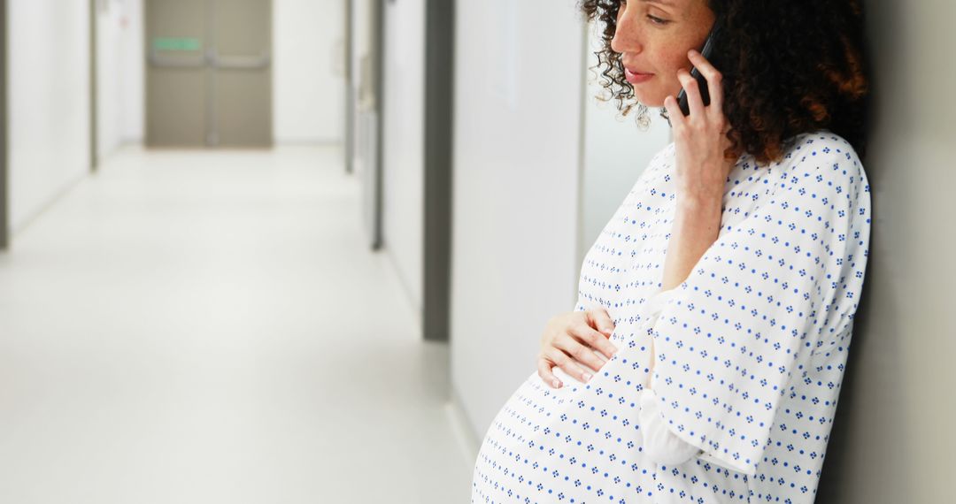 Pregnant Woman in Hospital Gown Talking on Phone in Hallway - Free Images, Stock Photos and Pictures on Pikwizard.com