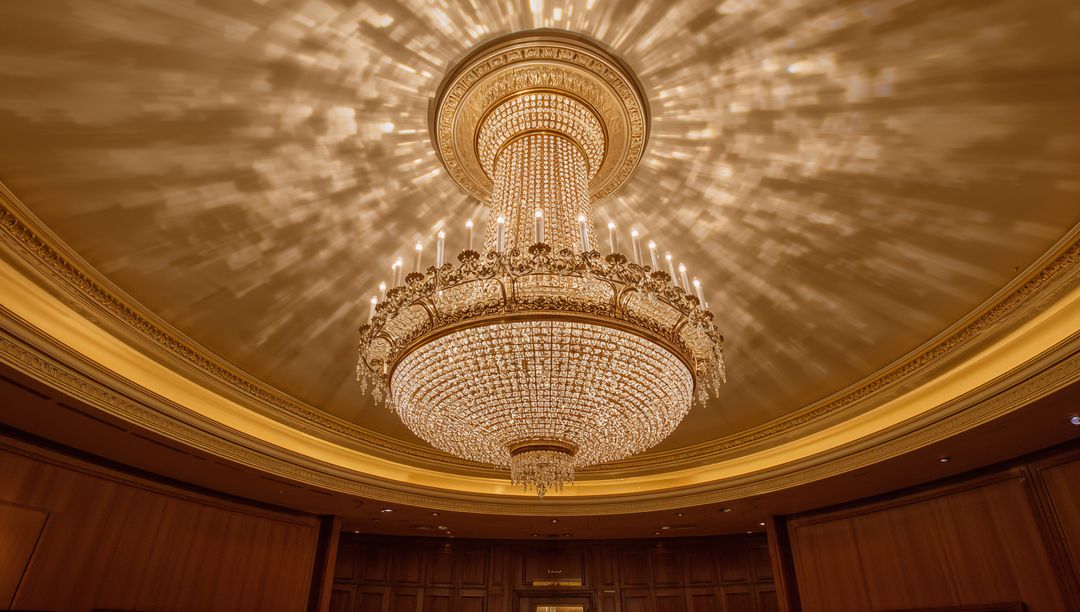 Opulent Crystal Chandelier Casting Starburst Light on Domed Ballroom Ceiling