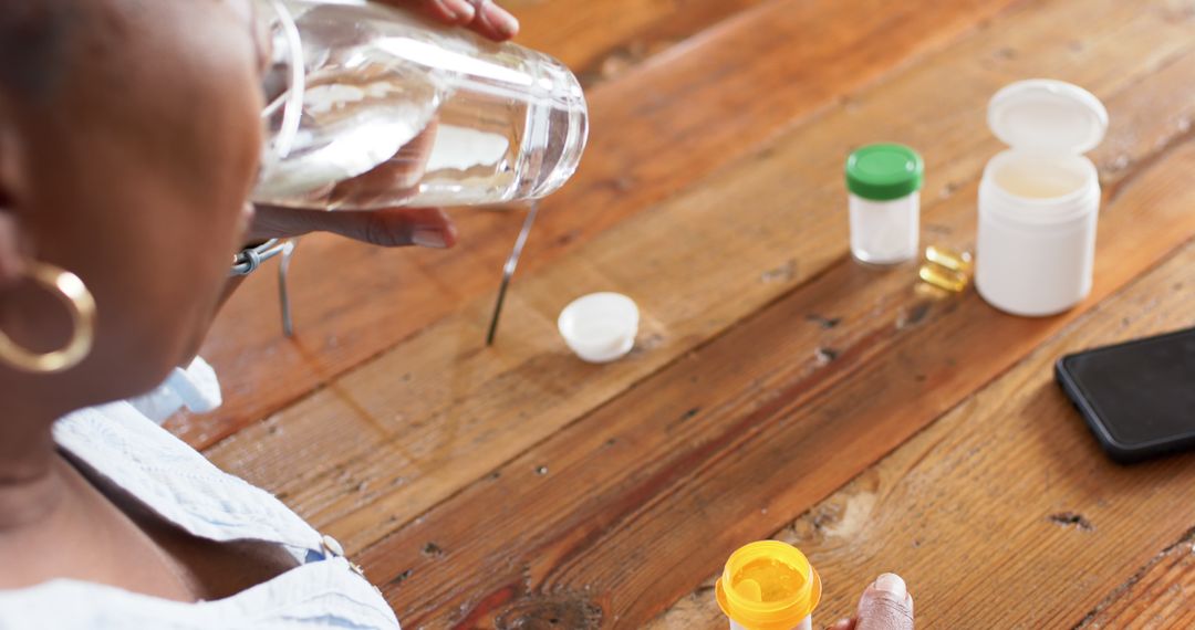 Person Taking Medication with Water at Wooden Table - Free Images, Stock Photos and Pictures on Pikwizard.com