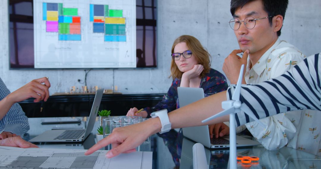 Diverse Team Collaborating on Blueprint with Modern Technology