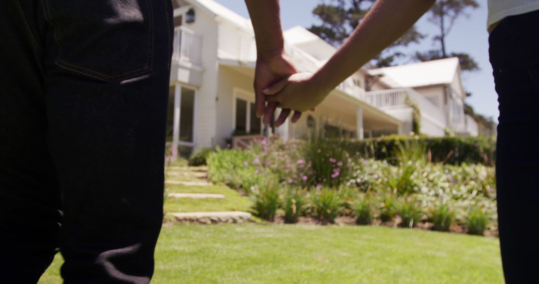 Rear midsection of diverse couple holding hands outside house in sunny garden, copy space - Free Images, Stock Photos and Pictures on Pikwizard.com