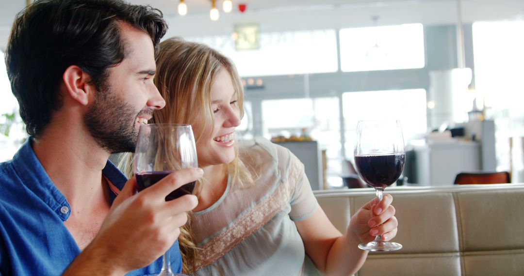 Joyful Couple Toasting with Red Wine in Sunny Restaurant