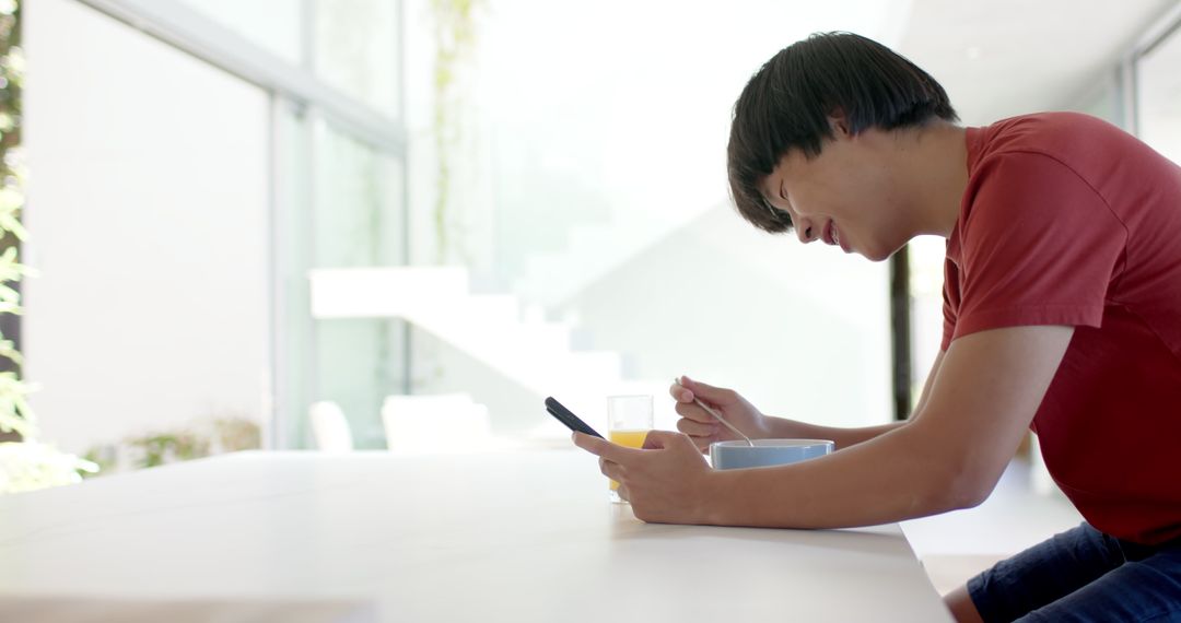 Asian College Student Browsing Smartphone During Breakfast