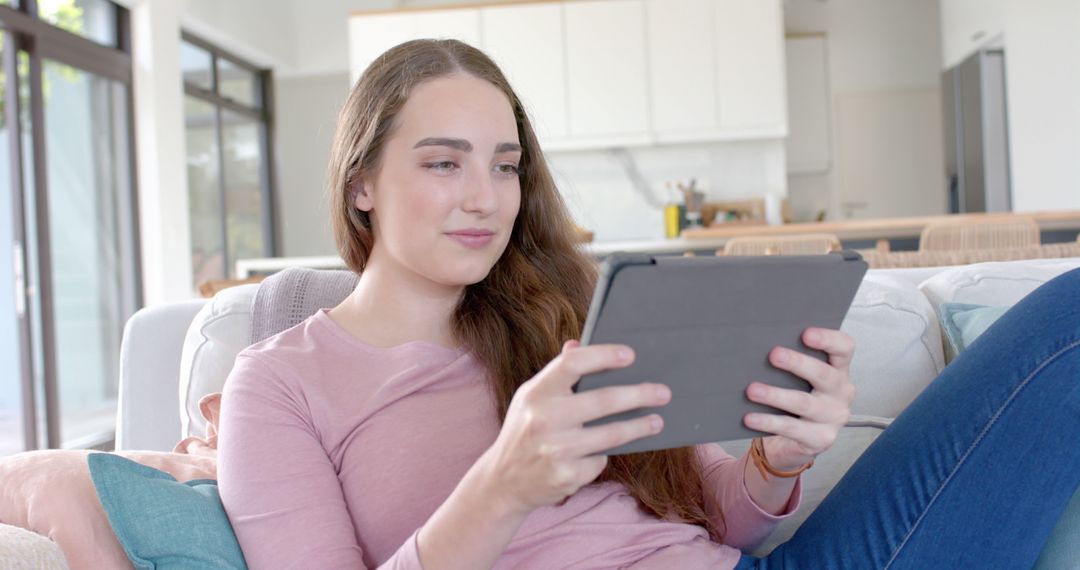 Young Woman Relaxing at Home Using Tablet for Leisure - Free Images, Stock Photos and Pictures on Pikwizard.com