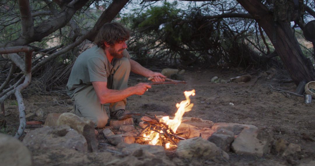 Man Starting Campfire Outdoors Amid Rocky Terrain - Free Images, Stock Photos and Pictures on Pikwizard.com