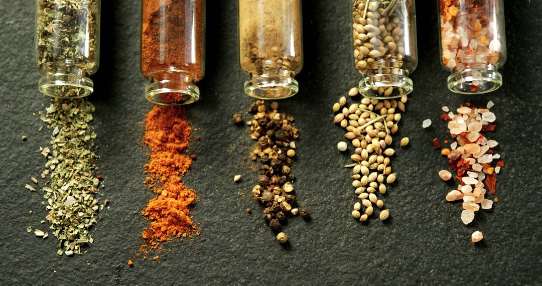 Variety of Spices Poured from Glass Bottles on Slate Surface - Free Images, Stock Photos and Pictures on Pikwizard.com