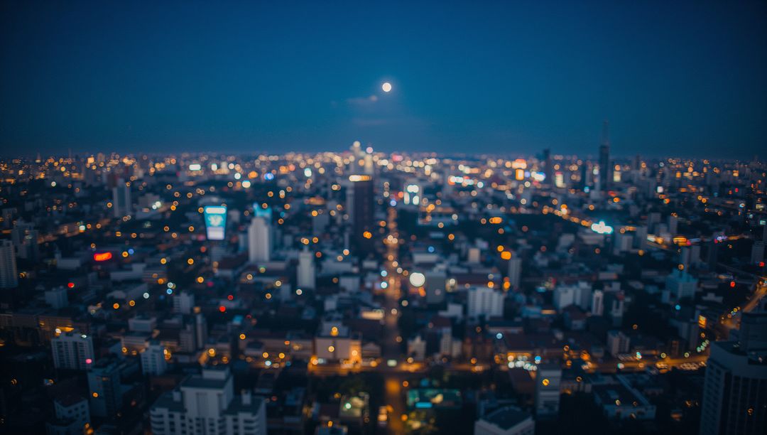 Blurred Urban Nightscape with Full Moon Over City Skyline