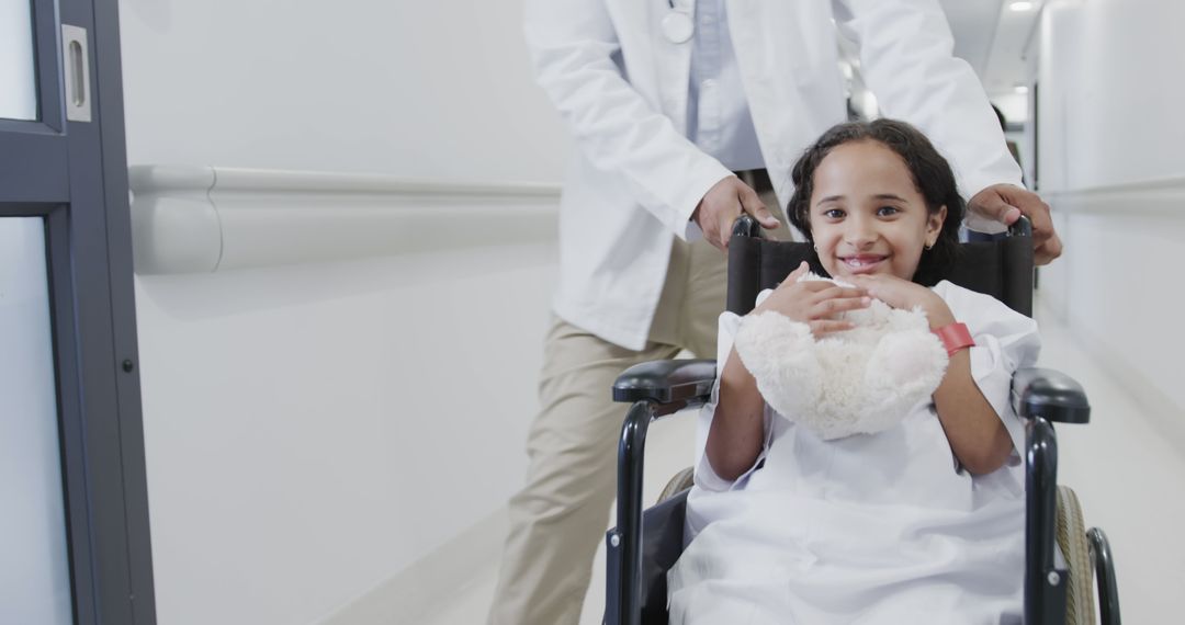 Happy Girl in Wheelchair Being Pushed by Doctor in Hospital Corridor - Free Images, Stock Photos and Pictures on Pikwizard.com