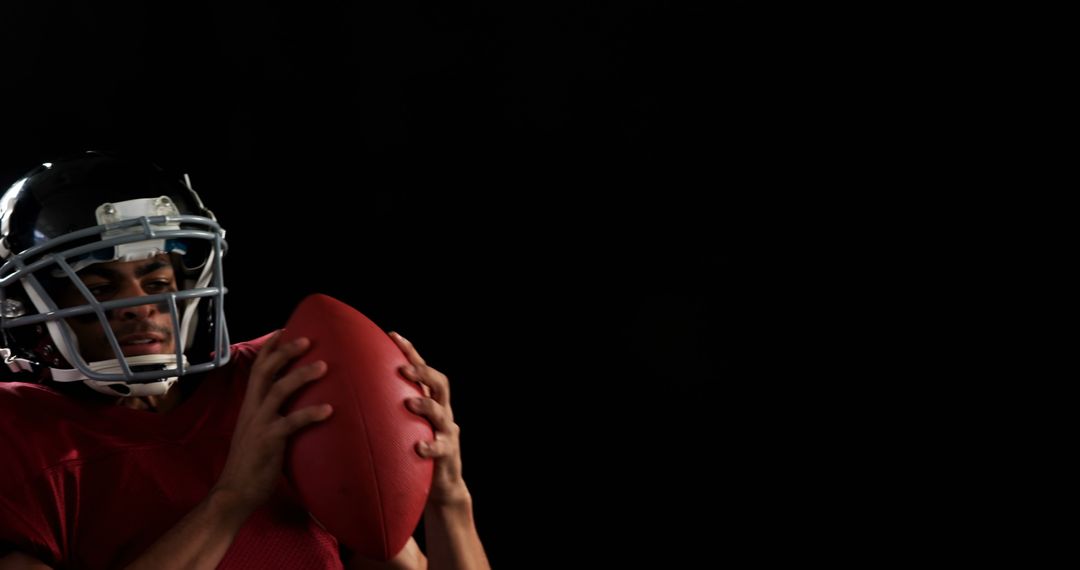 Football Player Holding Ball in Dim Lighting on Black Background - Free Images, Stock Photos and Pictures on Pikwizard.com