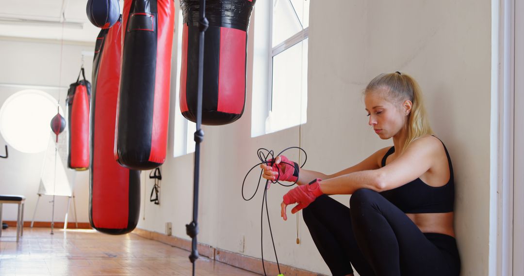 Young Woman Resting in Gym with Punching Bags, Post-Workout - Free Images, Stock Photos and Pictures on Pikwizard.com