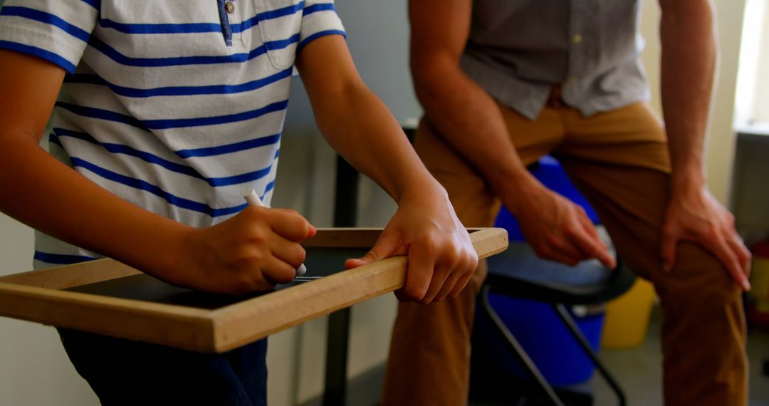 Teacher Guiding Young Student with Chalkboard Learning