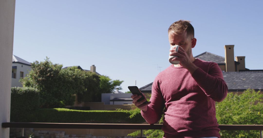 Man Drinking Coffee While Checking Smartphone on Outdoor Balcony - Free Images, Stock Photos and Pictures on Pikwizard.com