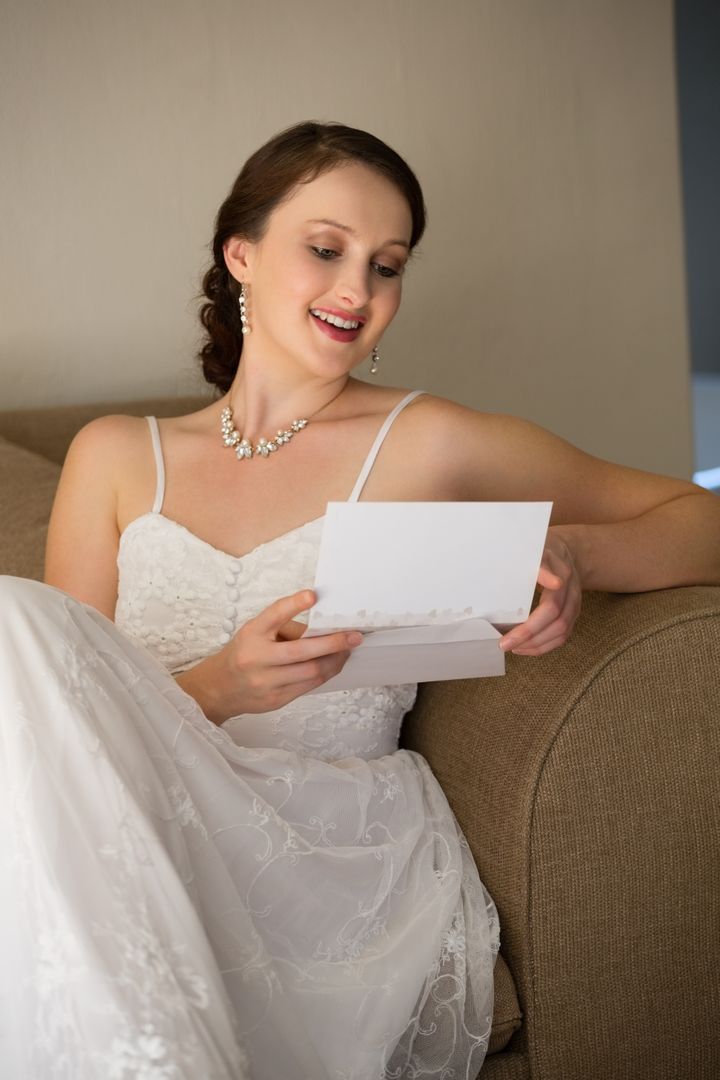Happy Bride Reading Wedding Card on Sofa - Free Images, Stock Photos and Pictures on Pikwizard.com