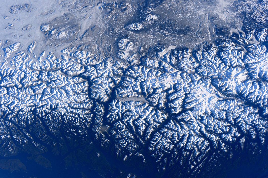 Aerial view of snow-covered mountain range under clear sky - Free Images, Stock Photos and Pictures on Pikwizard.com