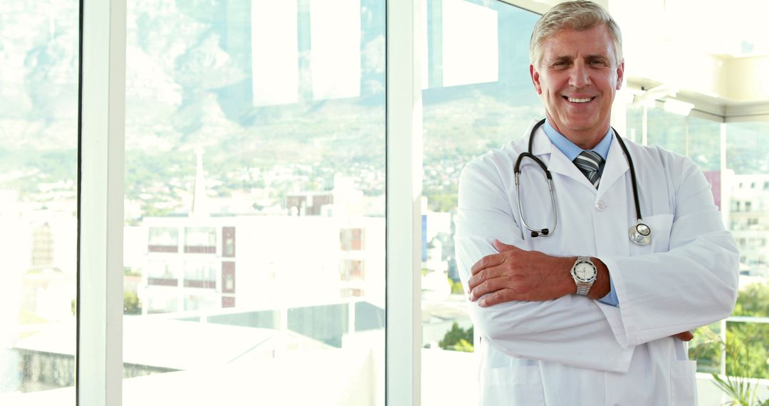 Confident Senior Doctor Standing with Arms Crossed in Modern Hospital - Free Images, Stock Photos and Pictures on Pikwizard.com