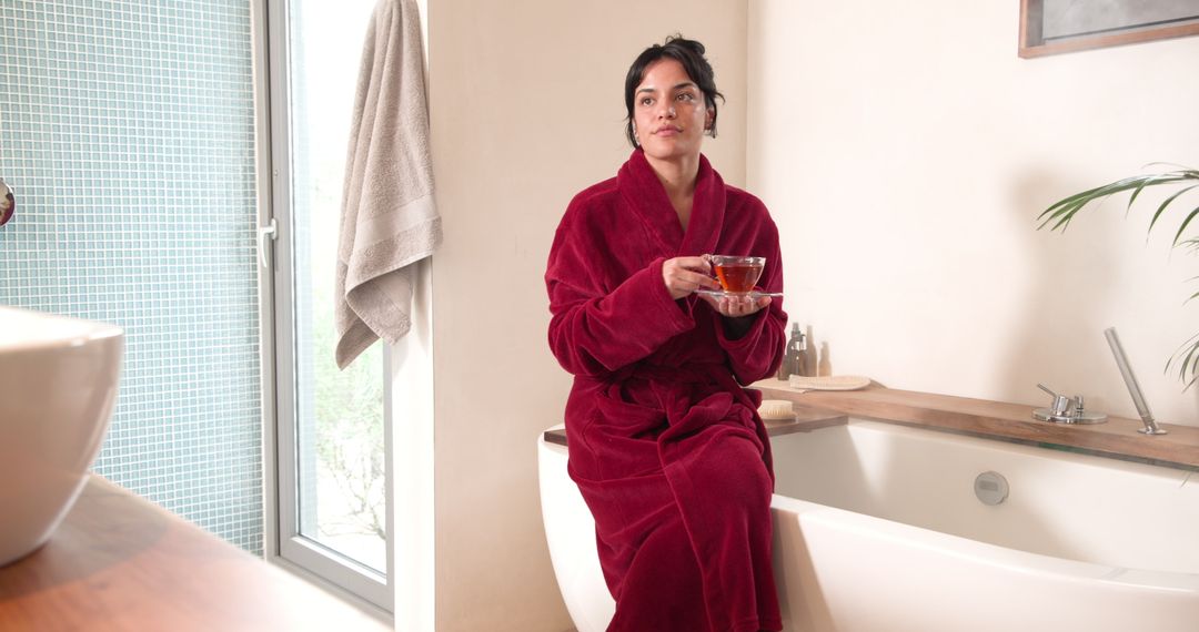 Woman in Red Robe Enjoying Tea in Elegant Bathroom Setting
