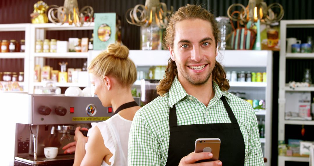 Smiling Barista in a Café Holding a Smartphone - Free Images, Stock Photos and Pictures on Pikwizard.com