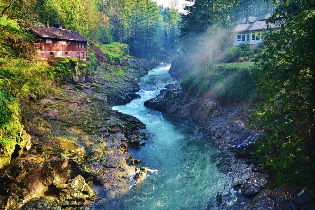 Serene River Flowing Through Forested Valley with Rustic Houses - Free Images, Stock Photos and Pictures on Pikwizard.com