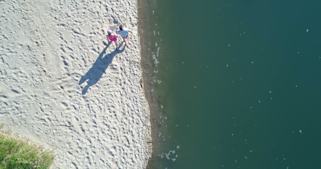 Aerial View of Couple Walking Along Sandy Beach Shoreline - Free Images, Stock Photos and Pictures on Pikwizard.com