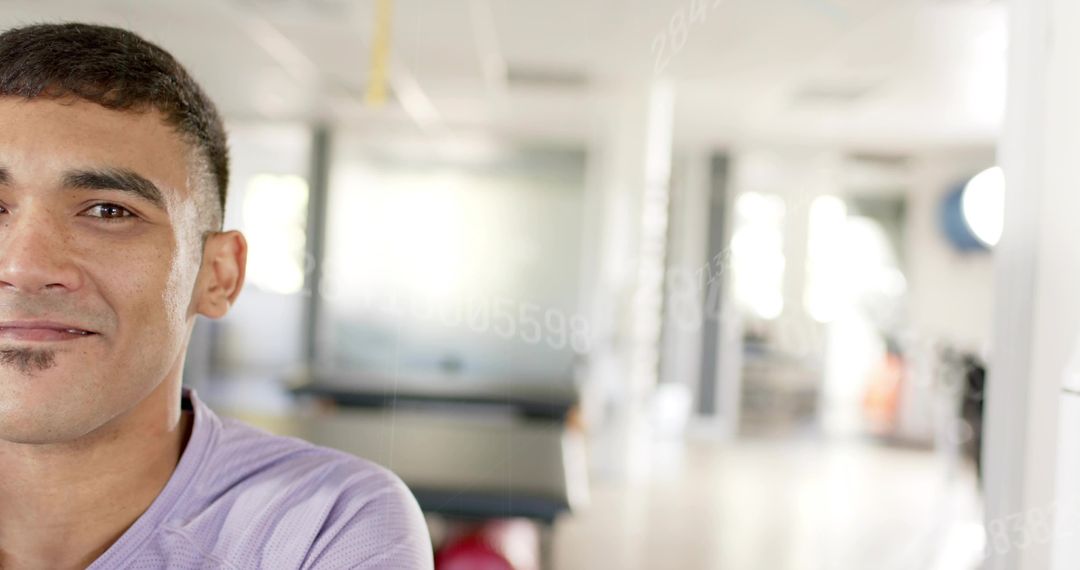 Smiling man facing camera in modern gym with bright windows and red exercise ball, copy space right